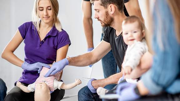 Junge Eltern bei der Erste-Hilfe-Ausbildung für Babys