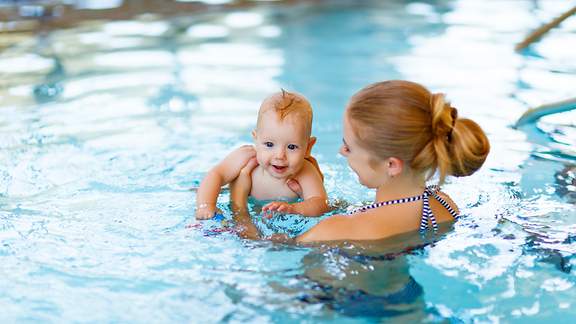 Eine Mutter hält ihr Baby im Schwimmbecken fest