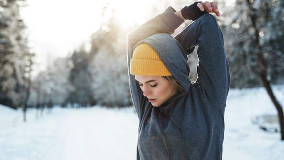 Junge athletische Frau beim Aufwärmen vor dem Wintertraining 