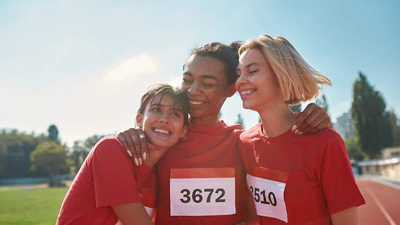 Drei Teilnehmerinnen an einem Marathon jubeln im Ziel